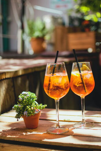 Auch in Kräuterschnaps sind Bitterstoffe: zwei Gläser mit Aperol auf einem Holztisch