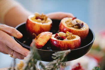 Wärmende Gewürze: zu sehen sind die Hände einer Frau, die eine Schale mit 3 gefüllten Bratäpfeln hält.