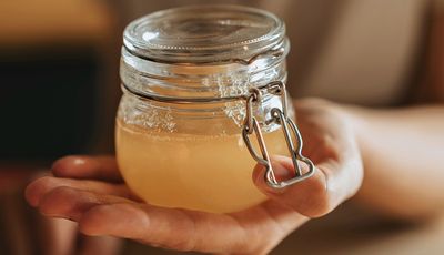 Selbst gemachter Sauerhonig in einem Einmachglas, gehalten auf einer ausgestreckten Hand